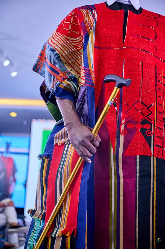 Close-up of a hand-woven robe and brass cane