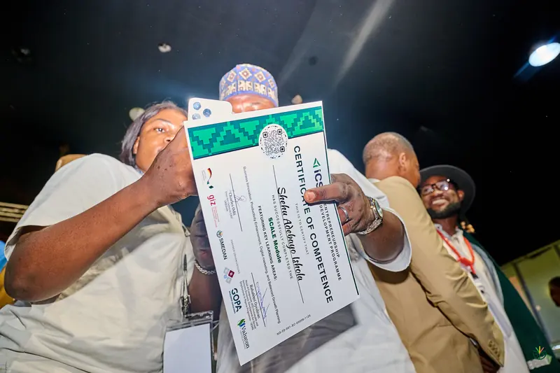 A graduate raises her certificate of completion