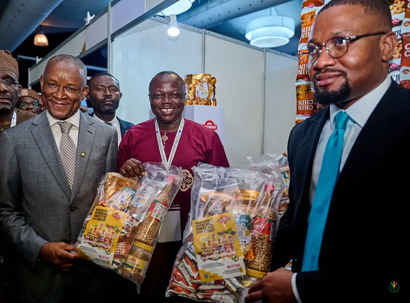 An exhibitor presents packaged products to visiting officials