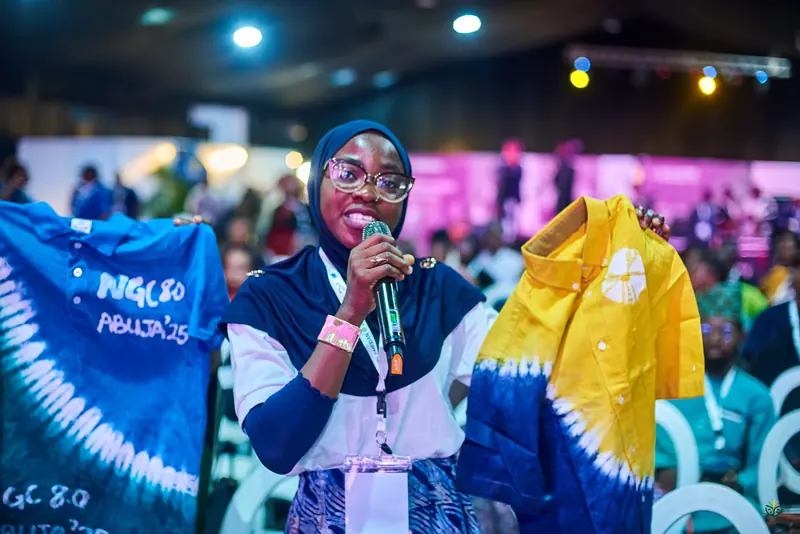 An exhibitor holds up hand-dyed fabric in the hall